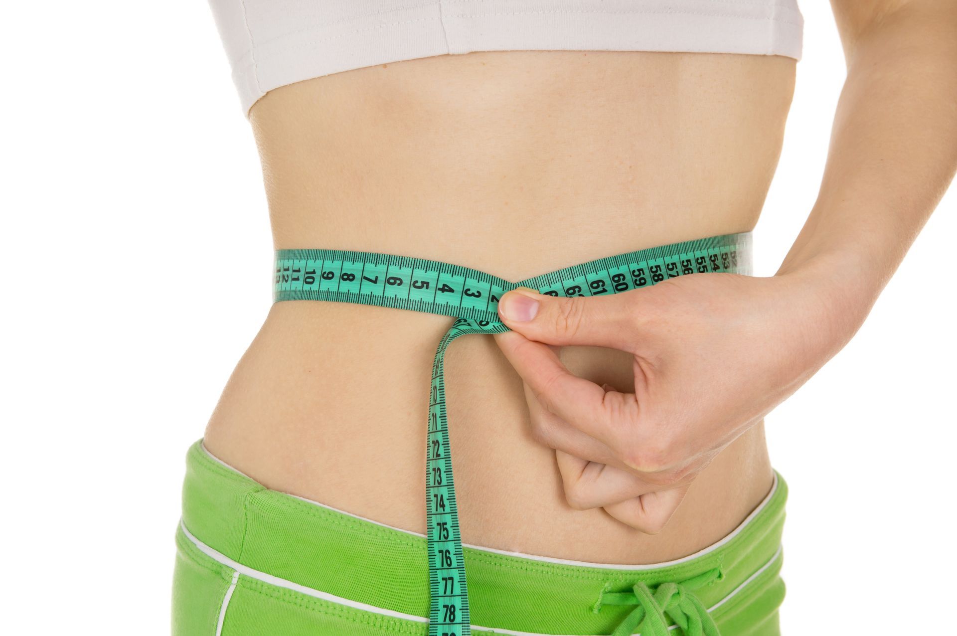 A woman is measuring her waist with a tape measure