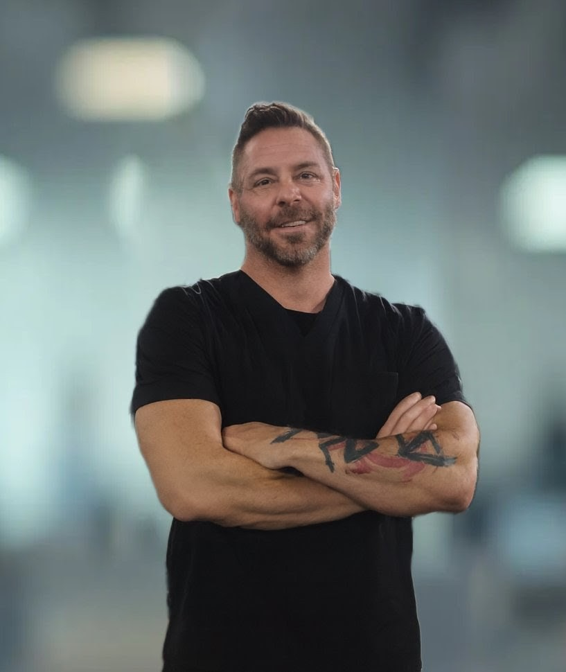 A man is sitting in a car holding a dog with its mouth open.