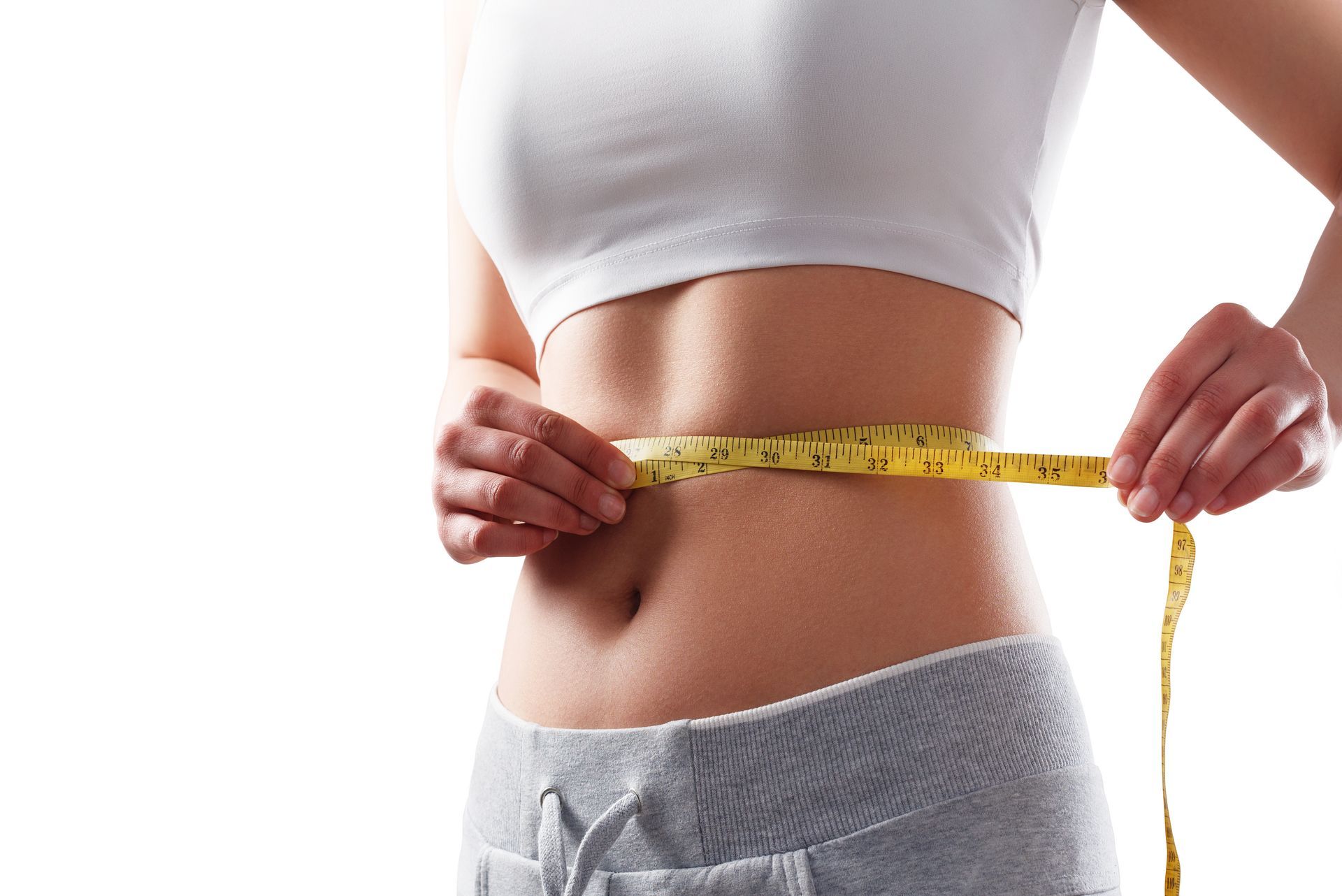 A woman is measuring her waist with a tape measure.