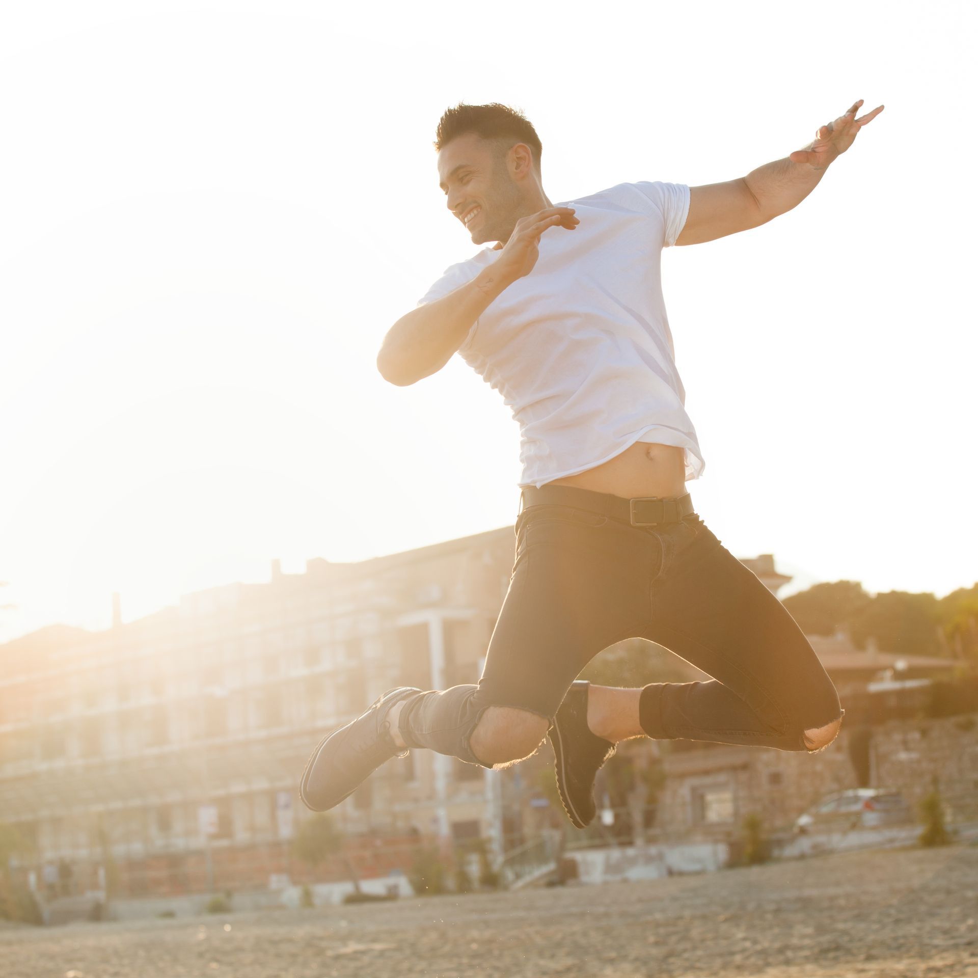 A man in a white shirt and black shorts is jumping in the air