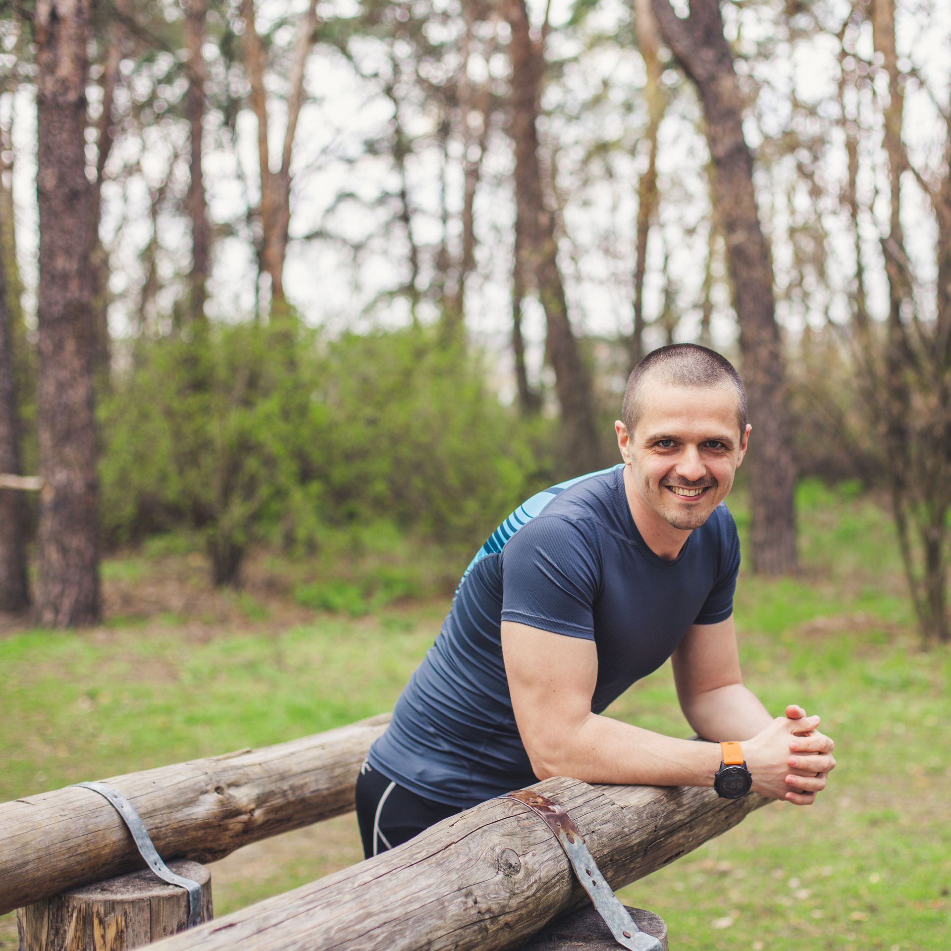 A man leaning on a wooden railing in the woods