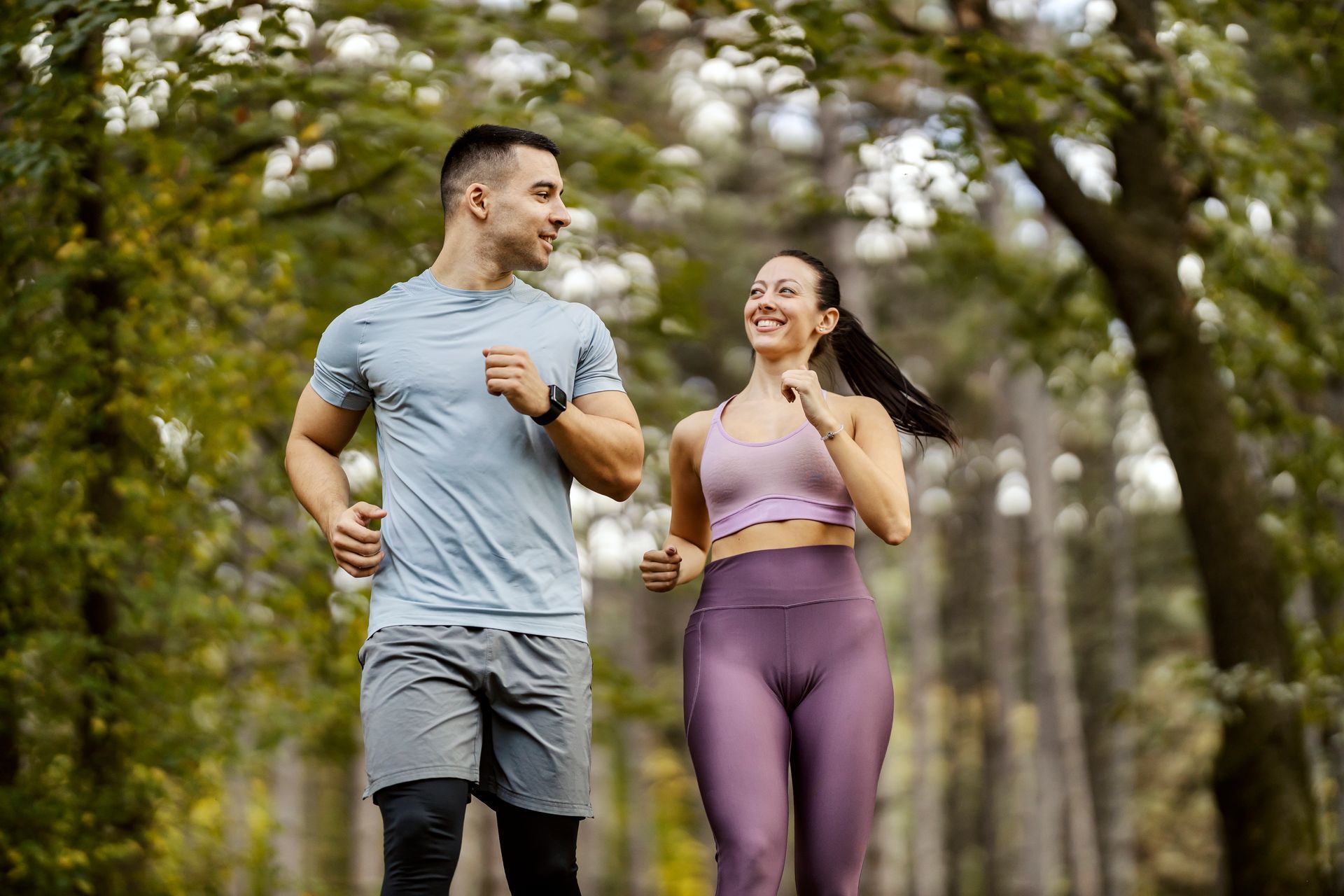 A man and a woman are jogging in a park.