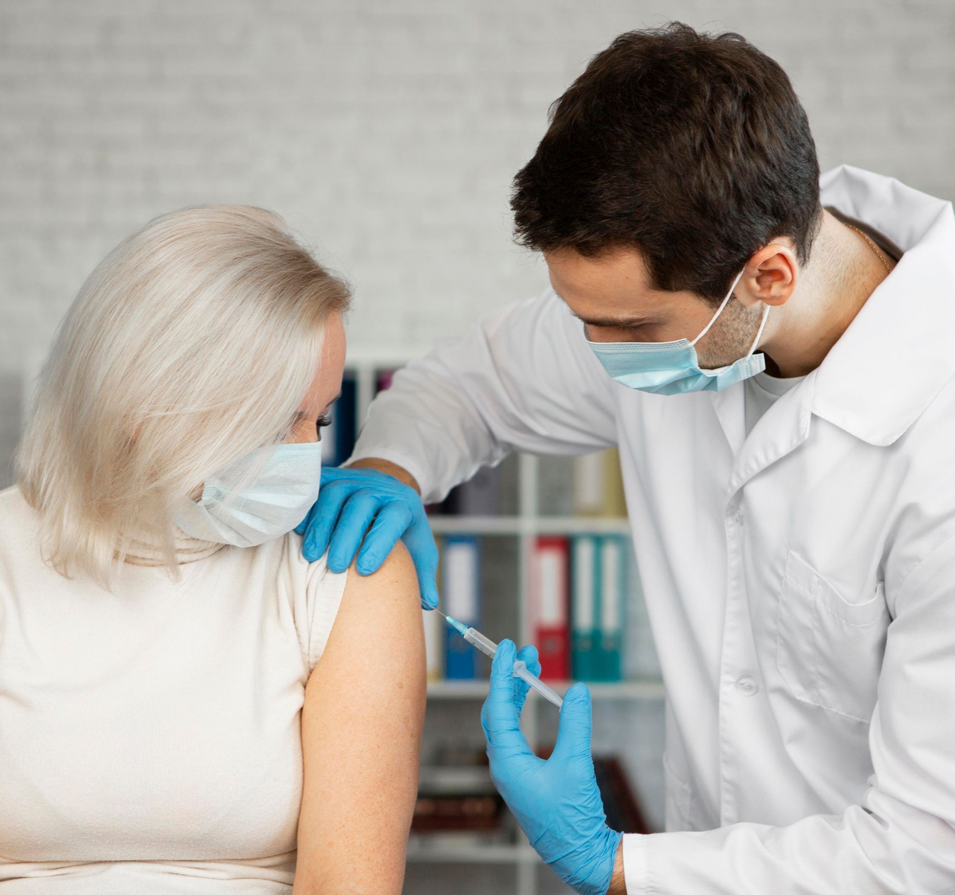 A doctor is giving a vaccine to a woman wearing a mask.