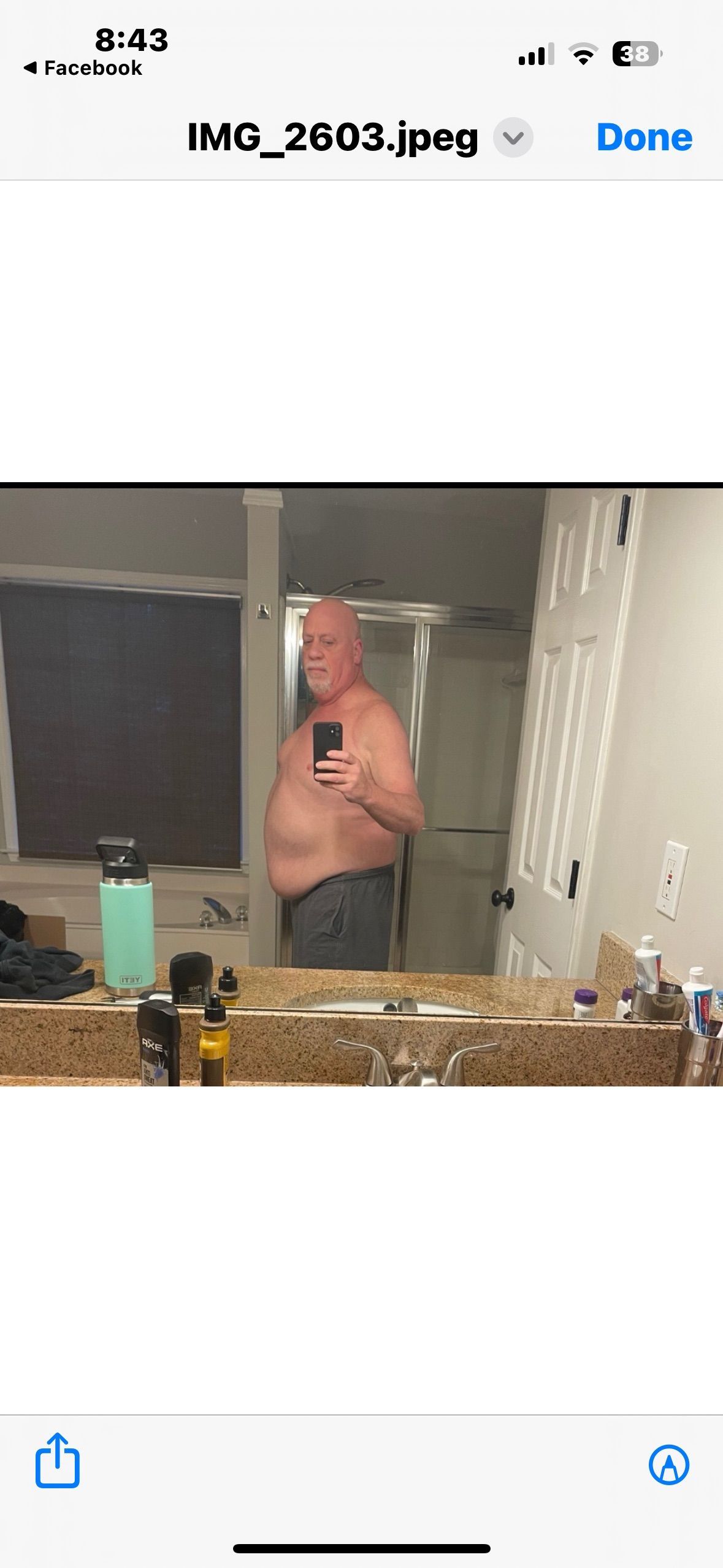 A shirtless man is taking a selfie in a bathroom mirror.