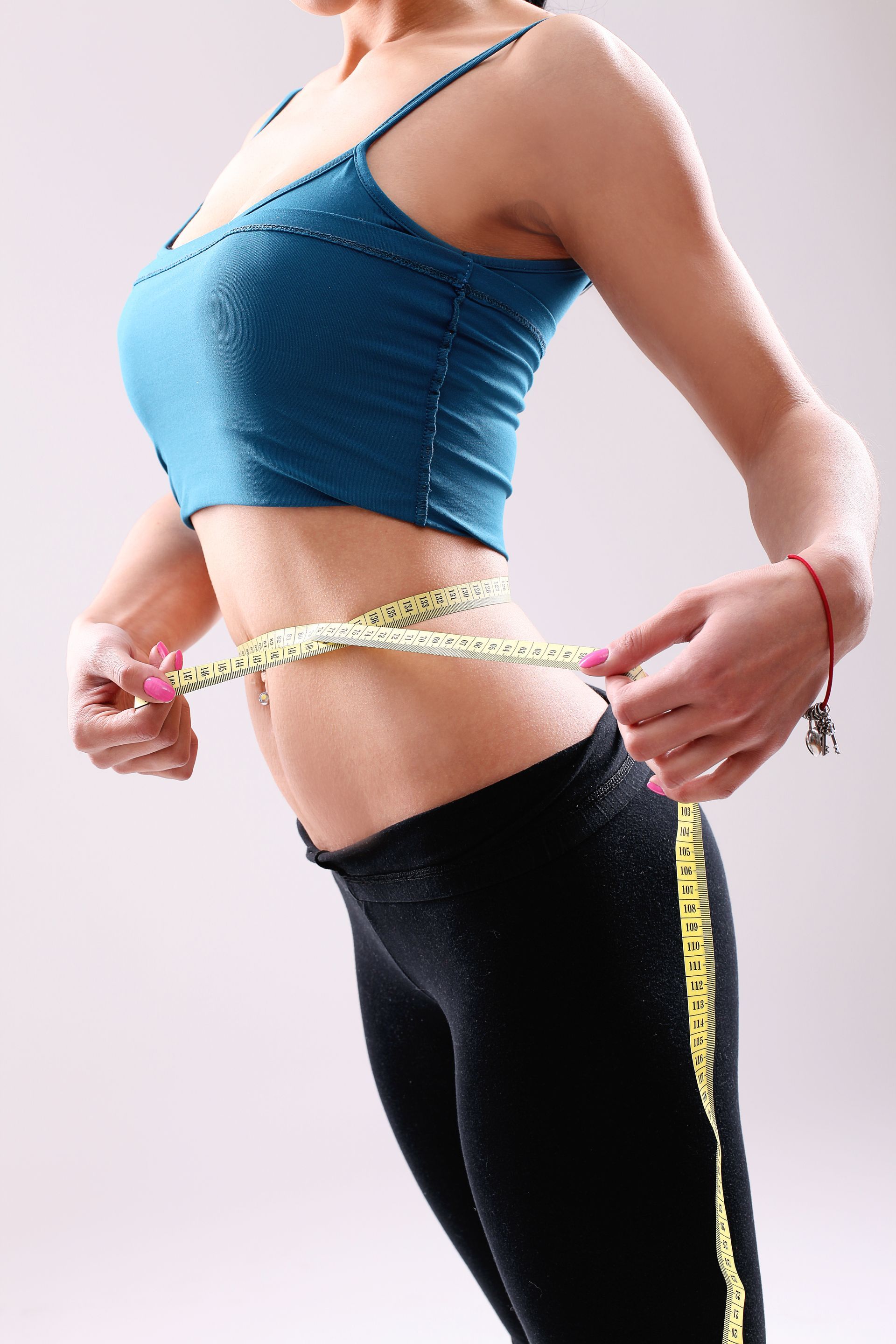 A woman is measuring her waist with a tape measure