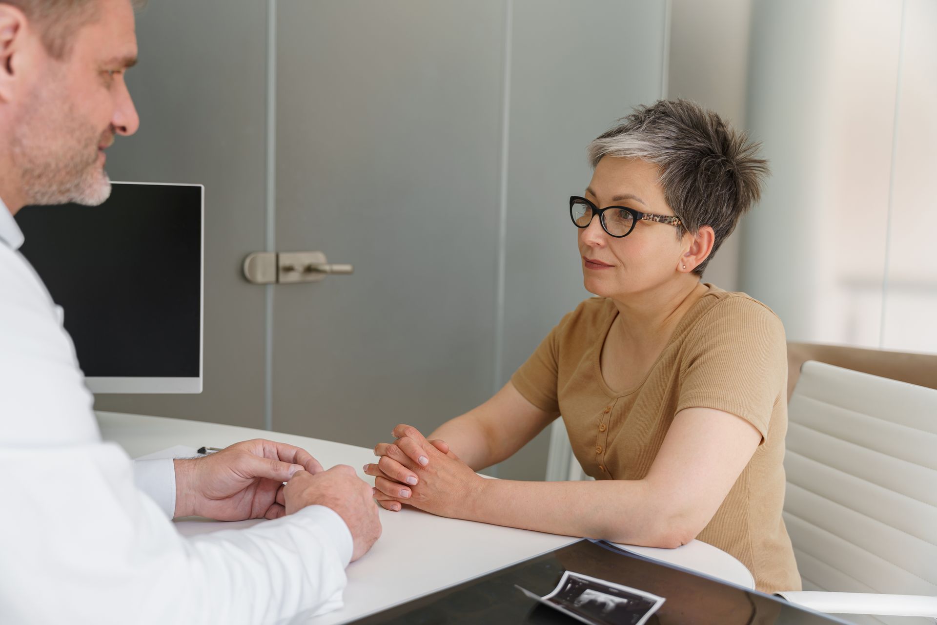 A man and a woman are sitting at a table talking to each other.