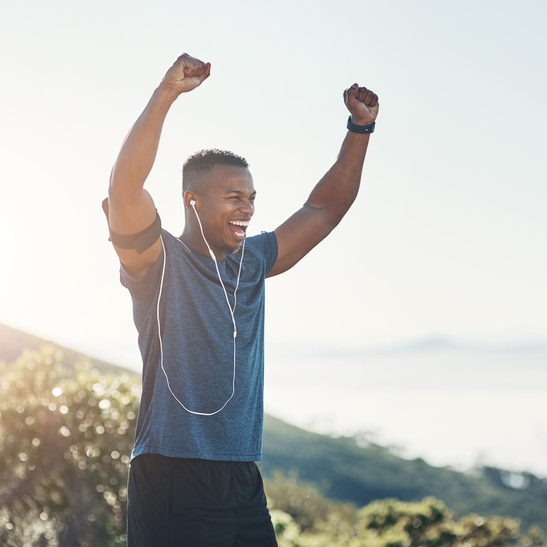 A man wearing headphones is standing with his arms in the air.