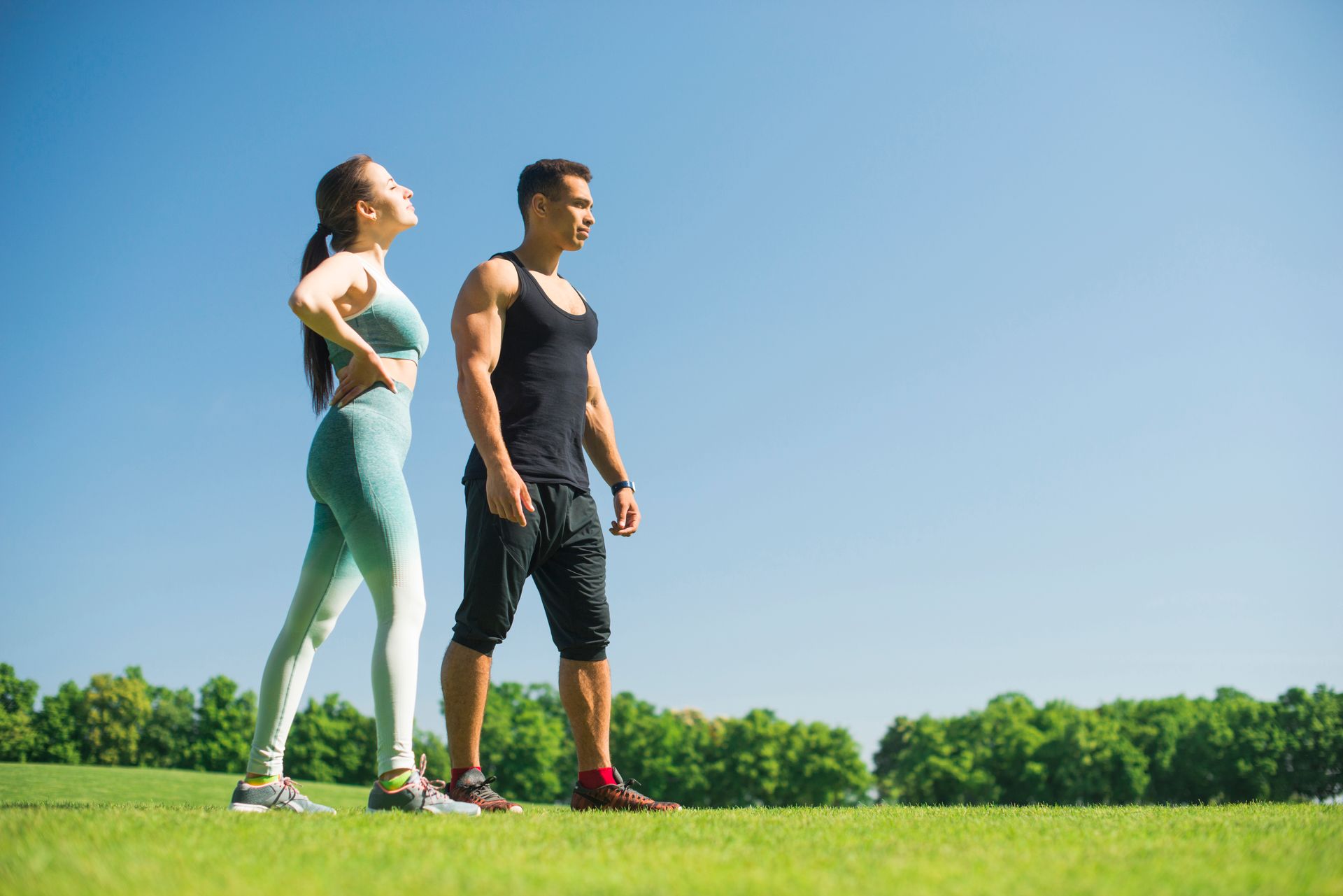 A man and a woman are standing next to each other in a grassy field.