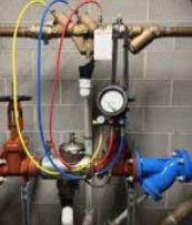 Architect's hands pointing at blueprints with a yellow hard hat, pencils, and calculator.