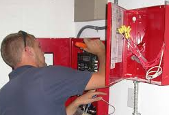 Firefighter holding a red fire extinguisher with nozzle, standing near a fire truck.