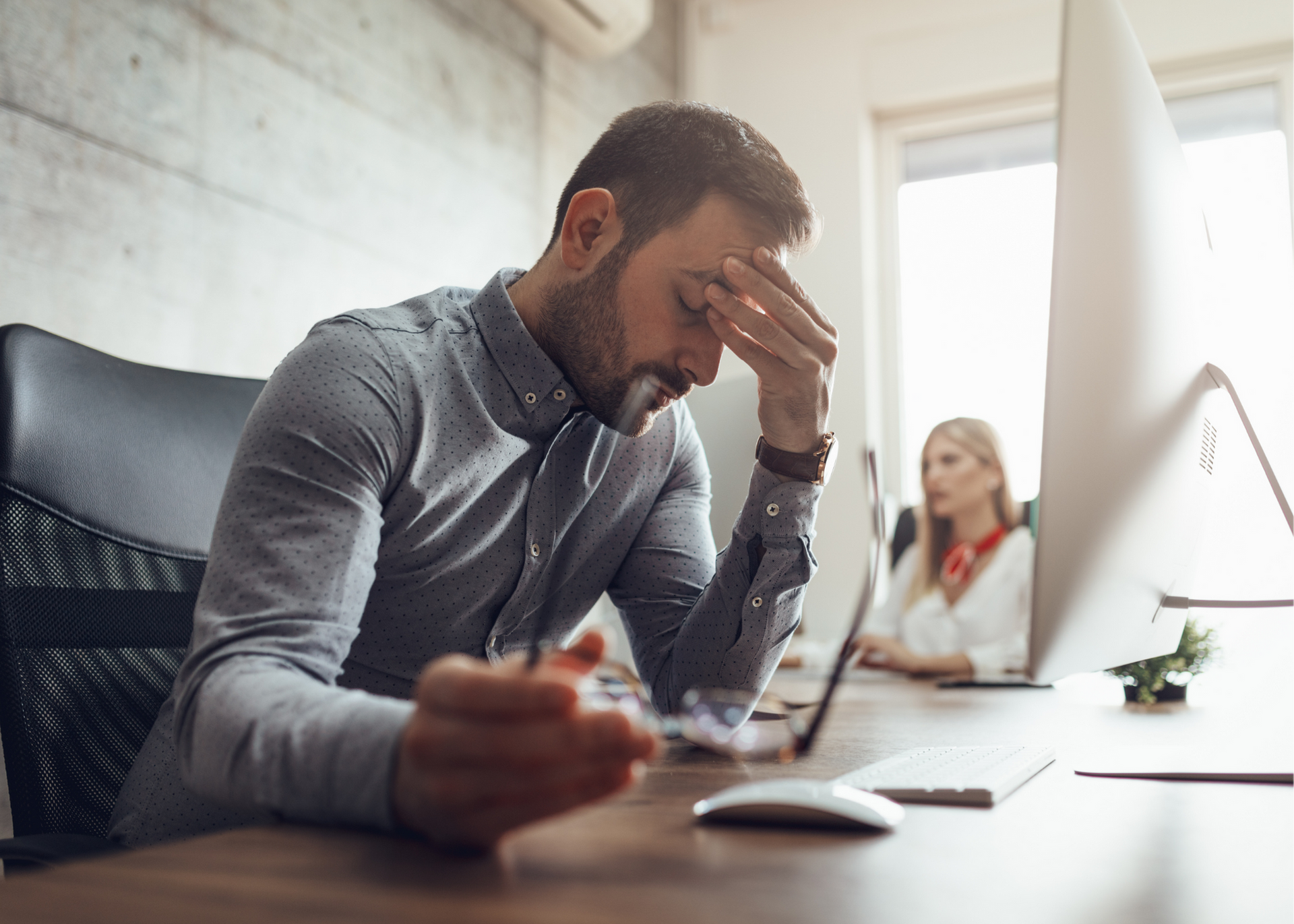 A man is sitting at a desk with his head in his hands.