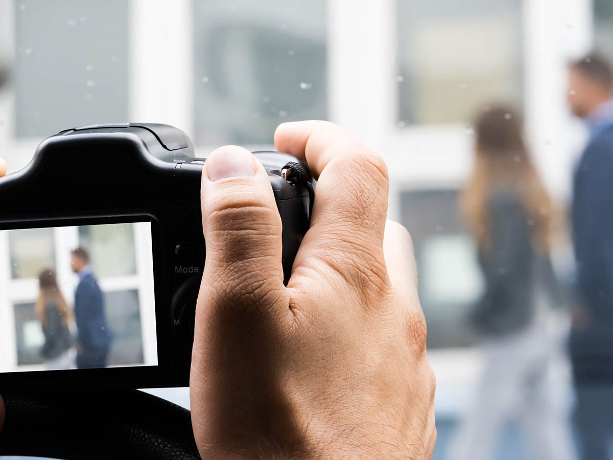 A person is taking a picture of a man and woman with a camera.