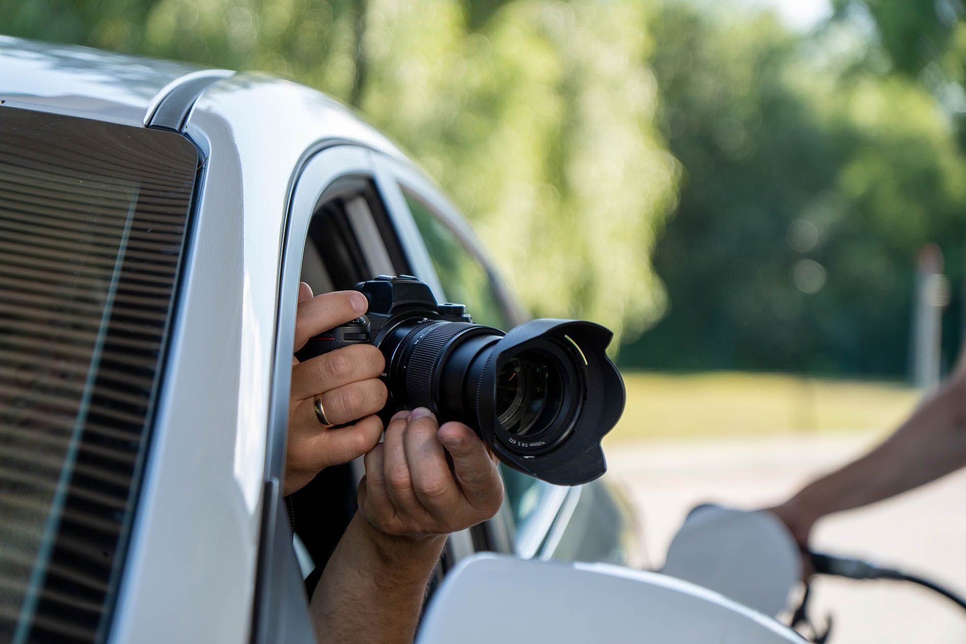 A person is holding a camera out of a car window.