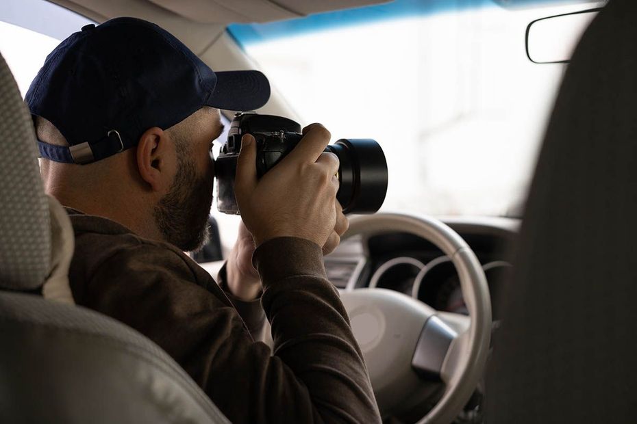 A man is sitting in a car taking a picture with a camera.