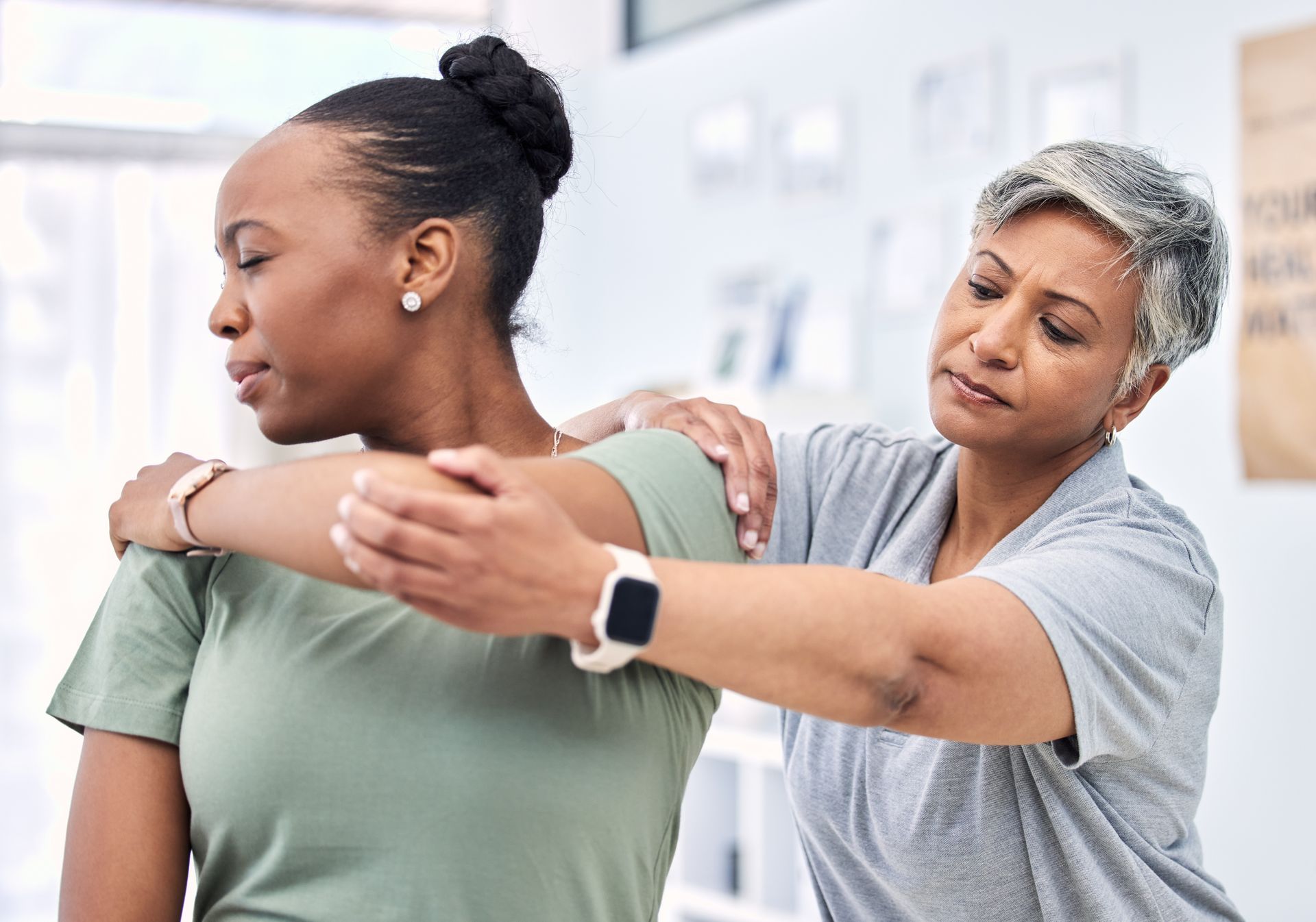 Physical therapist guiding a patient through an arm stretch in a bright clinic