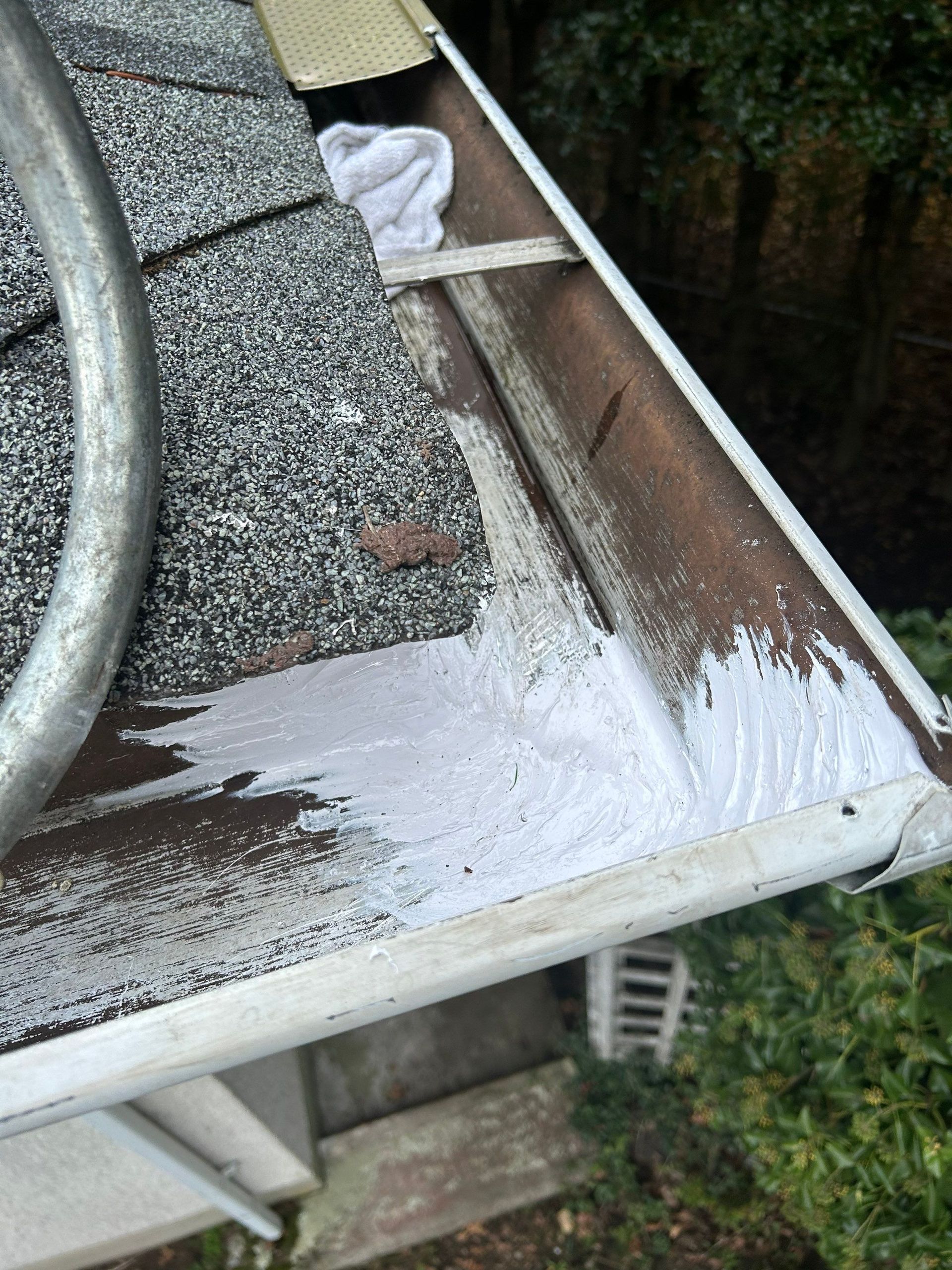 Section of a roof gutter, brown and white, with white sealant.
