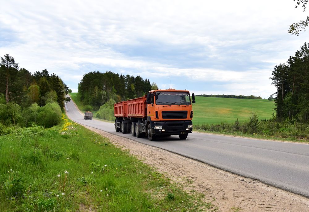 Orange Dump Truck Driving on a Rural Road — B&T Earthworks & Civil in Redlynch, QLD