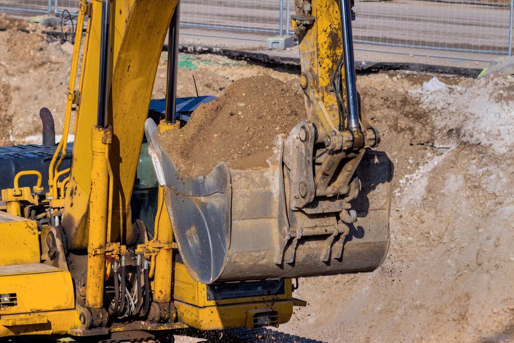 Yellow Excavator Bucket Filled With Dirt at a Construction Site — B&T Earthworks & Civil in Smithfield, QLD