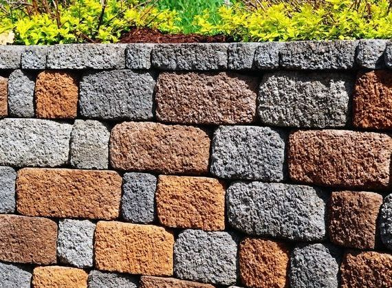 Stone Wall With Varying Colors, Topped With Green Foliage — B&T Earthworks & Civil in Smithfield, QLD