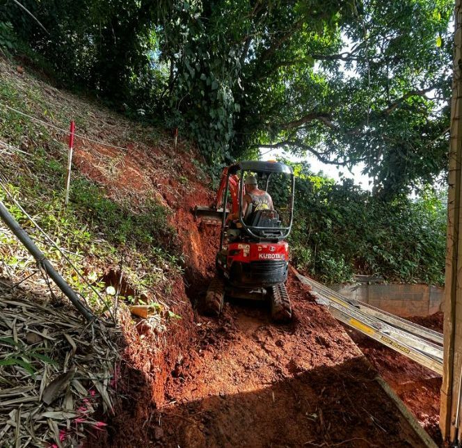 Small Excavator on a Muddy Hillside, Operator at the Controls — B&T Earthworks & Civil in Yorkeys Knob, QLD