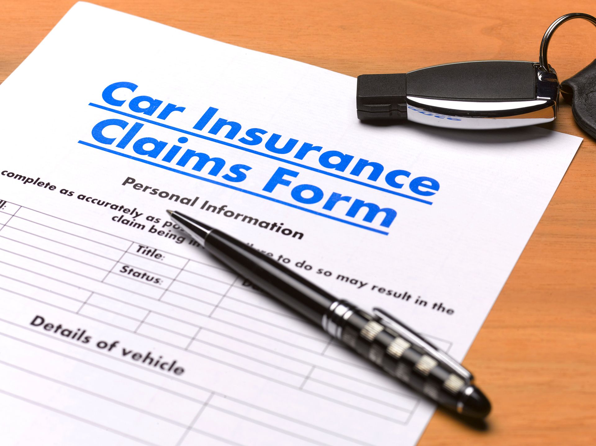A car insurance claims form with a pen and keys