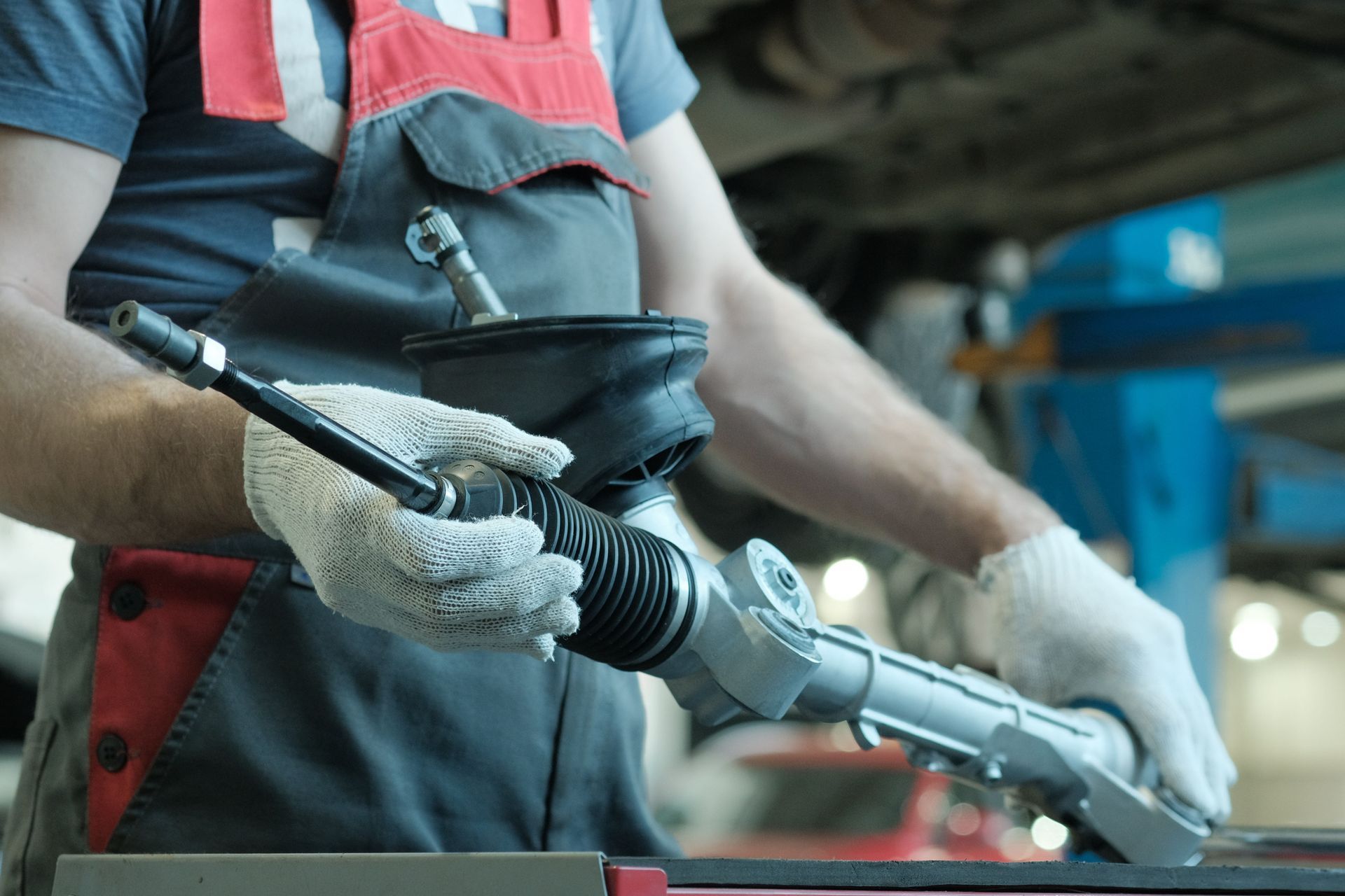 A man is working on a steering rack in a garage.