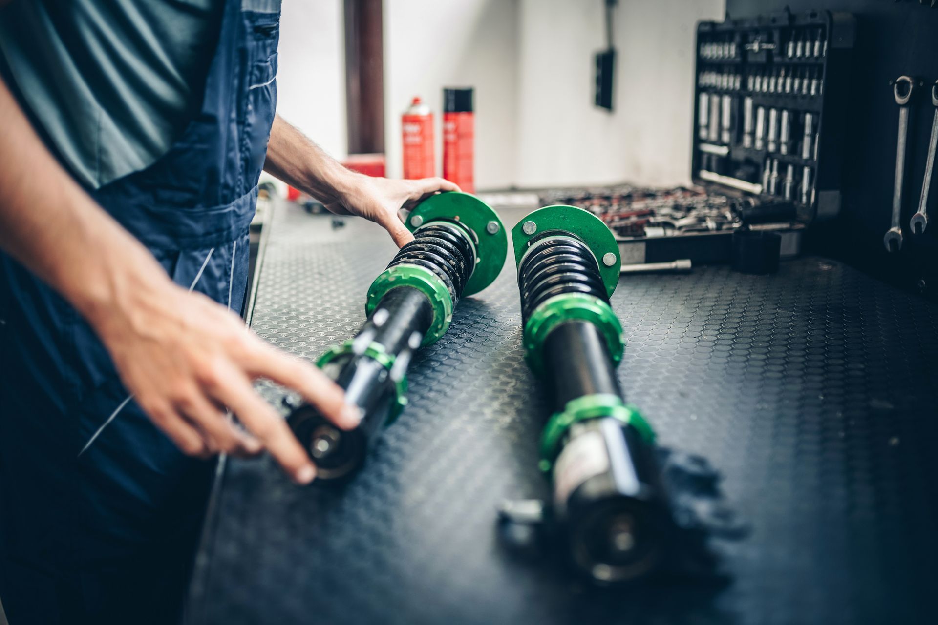 A man is holding a pair of shock absorbers on a table.