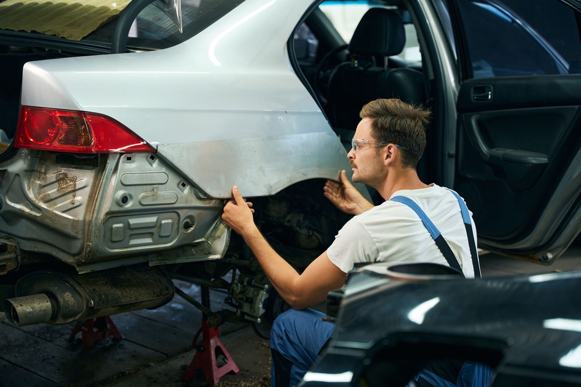 A man is working on the back of a car in a garage.