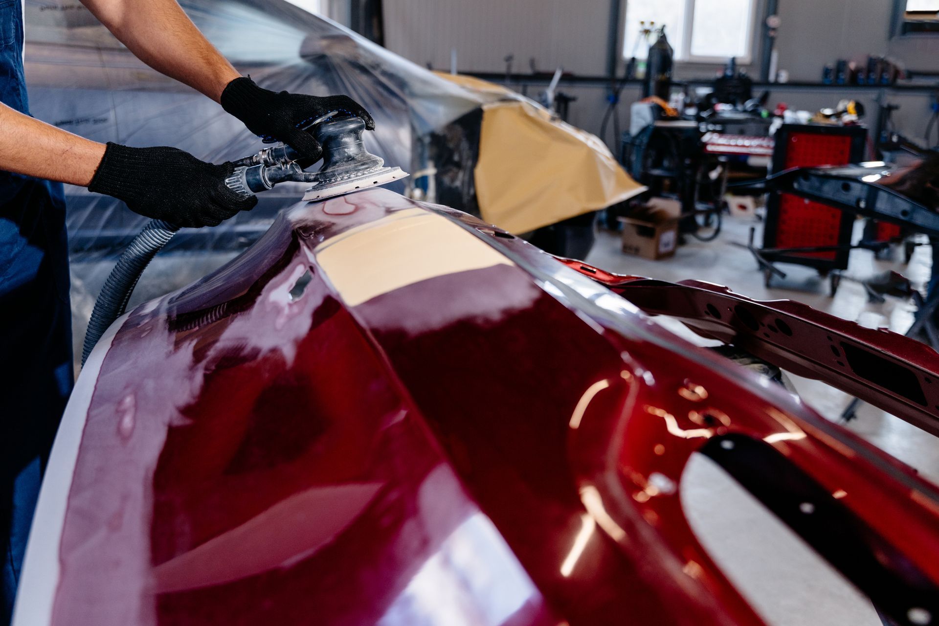 A man is painting a red car in a garage.