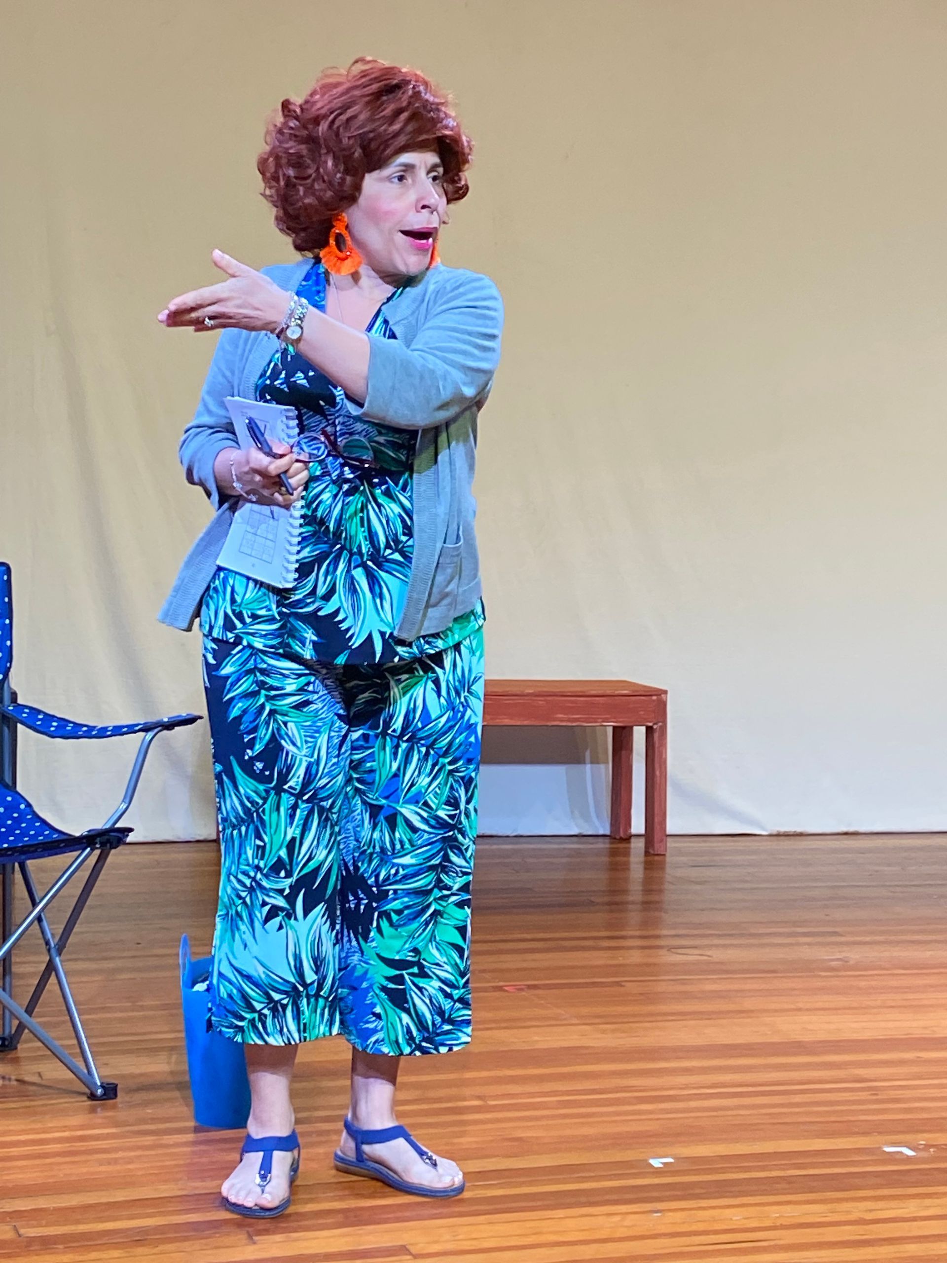 A male actor dressed as a women in a wig and tropical dress