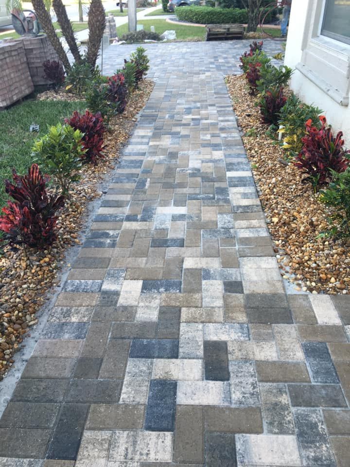 A walkway with bricks and plants along the side of it