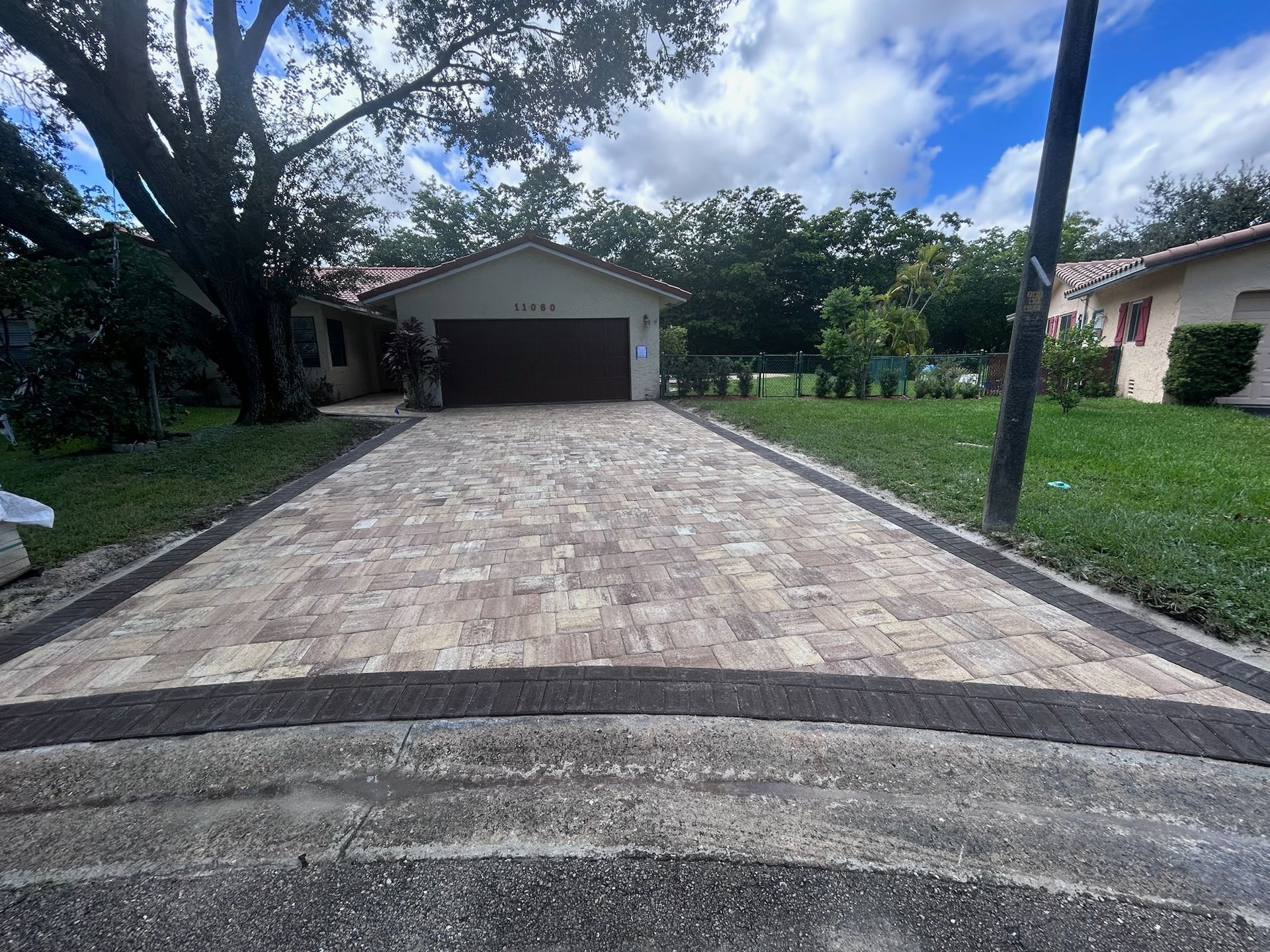 A driveway leading to a house with a garage and a tree in the background.