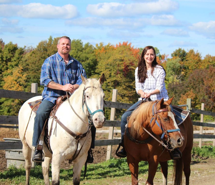 A man and a woman are riding horses in a field