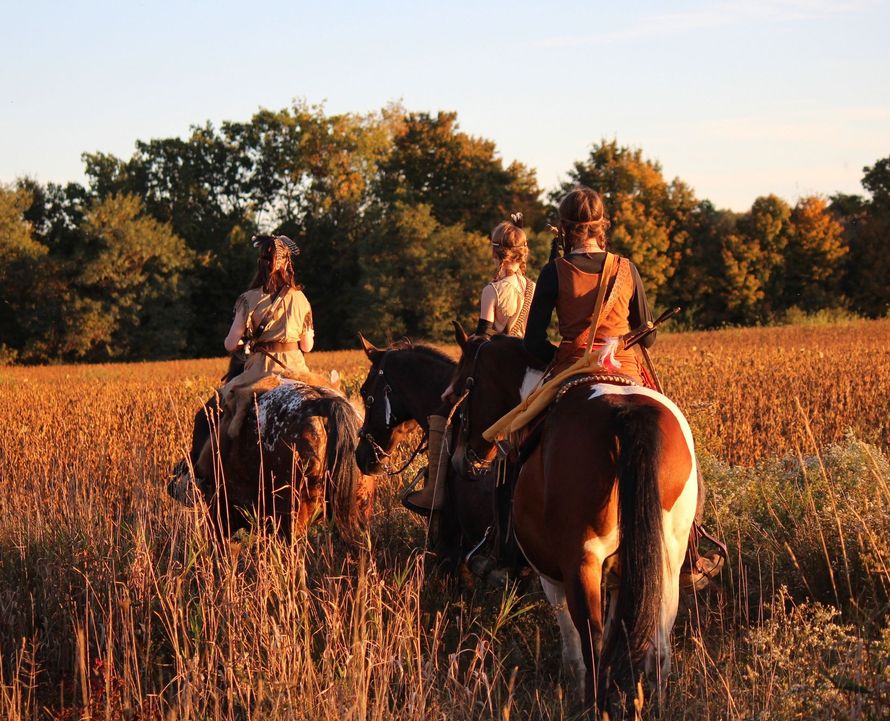 A man and a woman are riding horses in a field