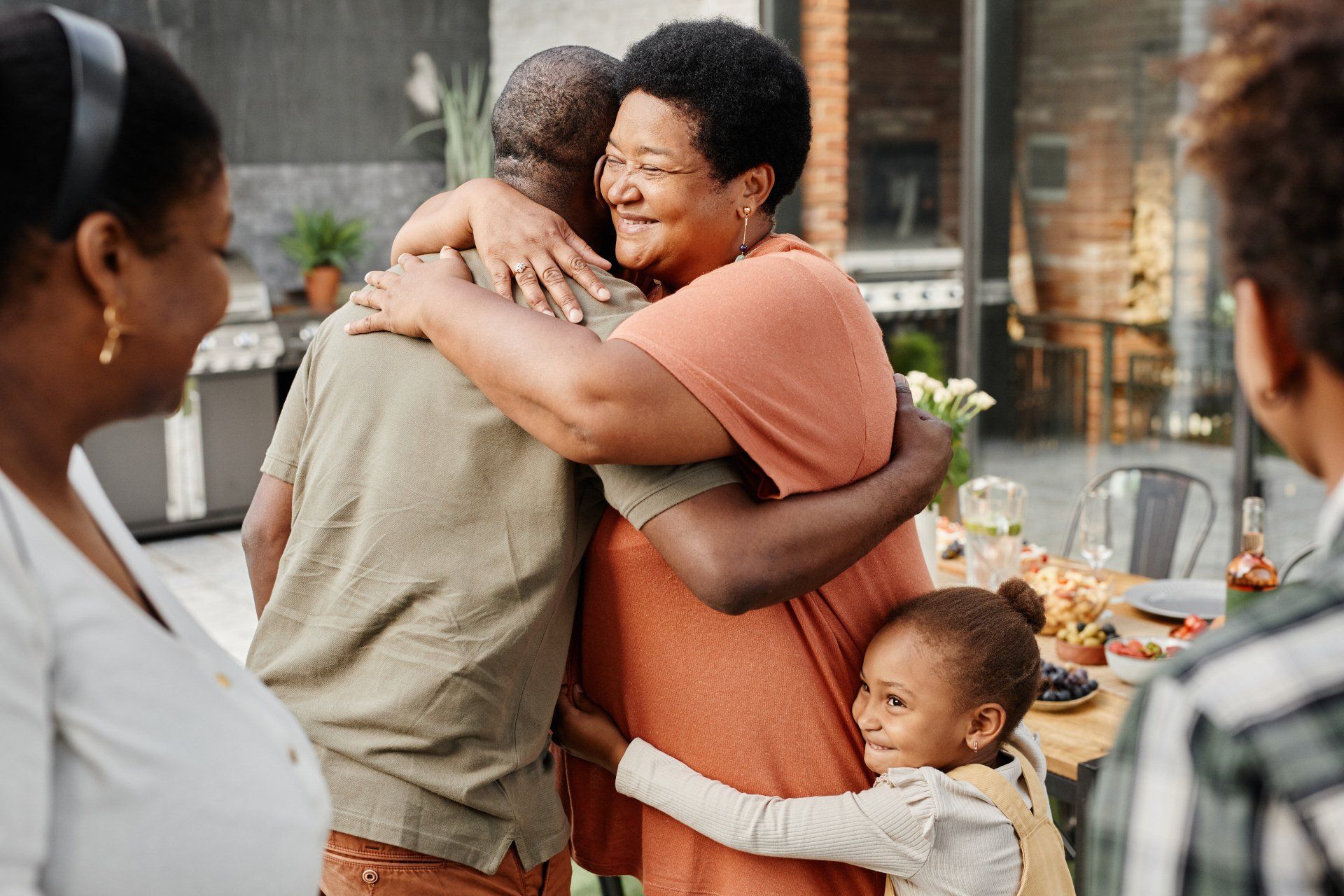 A group of people are hugging each other at a dinner table.