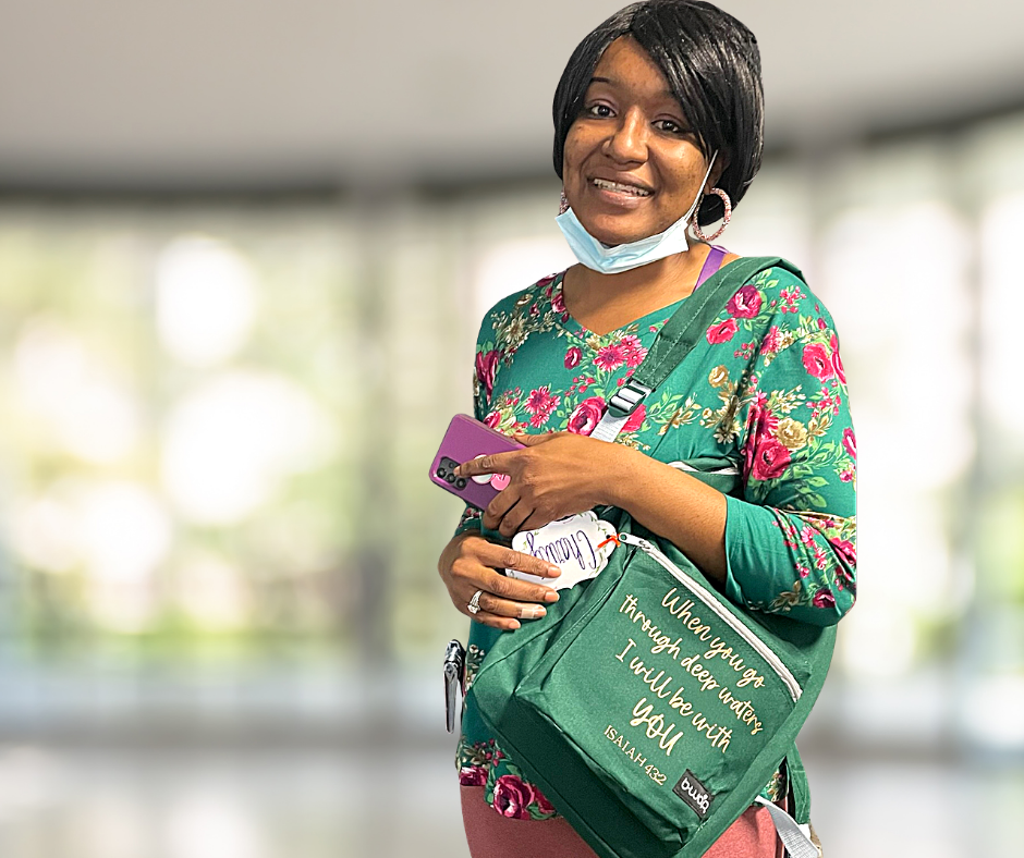 Woman smiles, holds phone, and a bag with text,