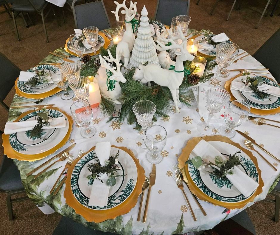 A table set for a christmas dinner with plates , utensils , candles and reindeer decorations.