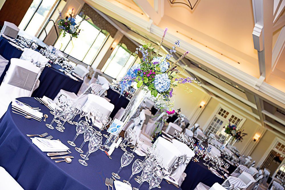 Elegant event space with round navy blue tables, floral centerpieces, and place settings.