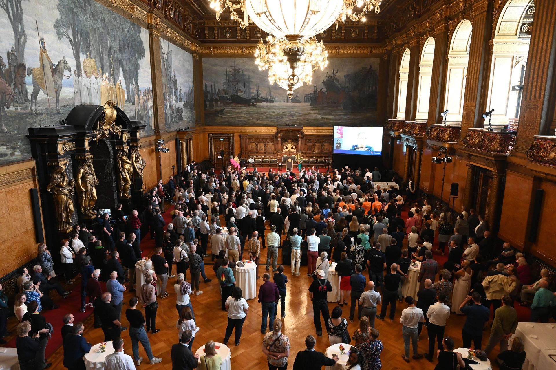 Große Menschenmenge im Hamburger Rathaus, die einer Veranstaltung mit Leinwand und dekorativen Wandgemälden beiwohnt. Kirstin Hammerstein, hammerstein-pictures