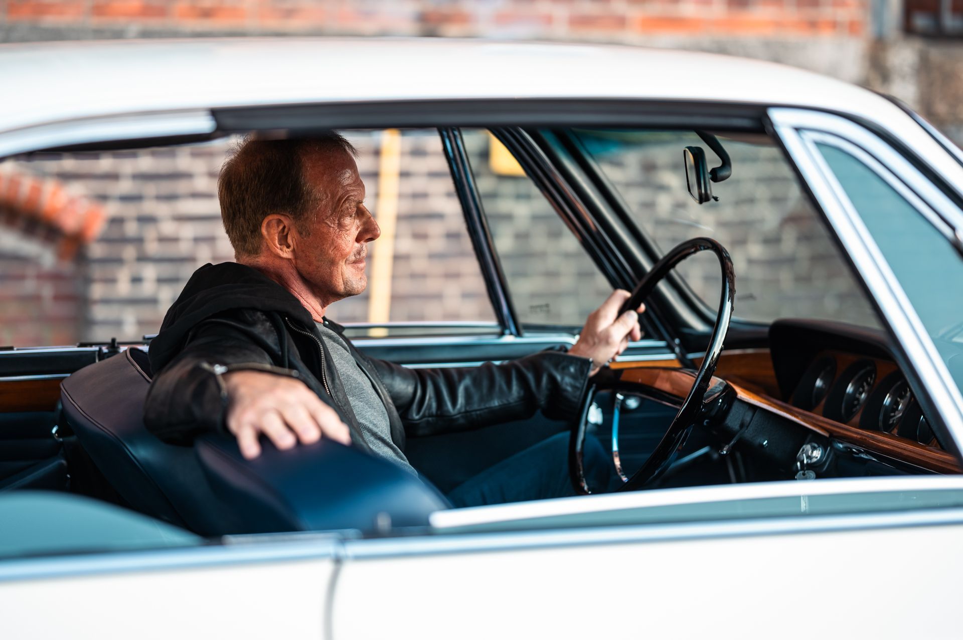 Mann fährt einen weißen Oldtimer, blickt nach vorne, Seitenprofil. Kirstin Hammerstein, hammerstein-pictures