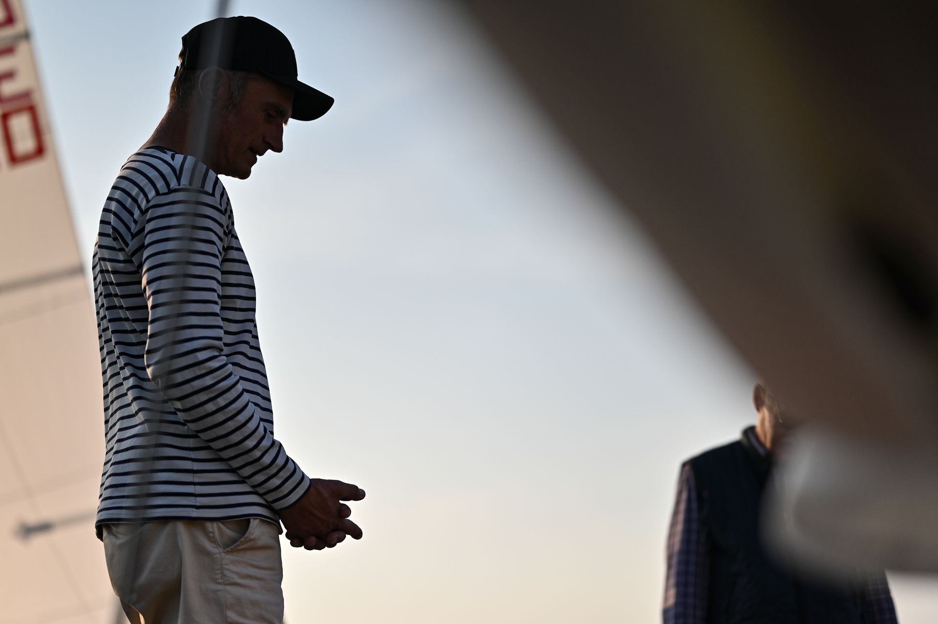 Mann in gestreiftem Hemd und Mütze auf einem Boot; blickt nach unten, verschwommene Gestalt. Kirstin Hammerstein, hammerstein-pictures