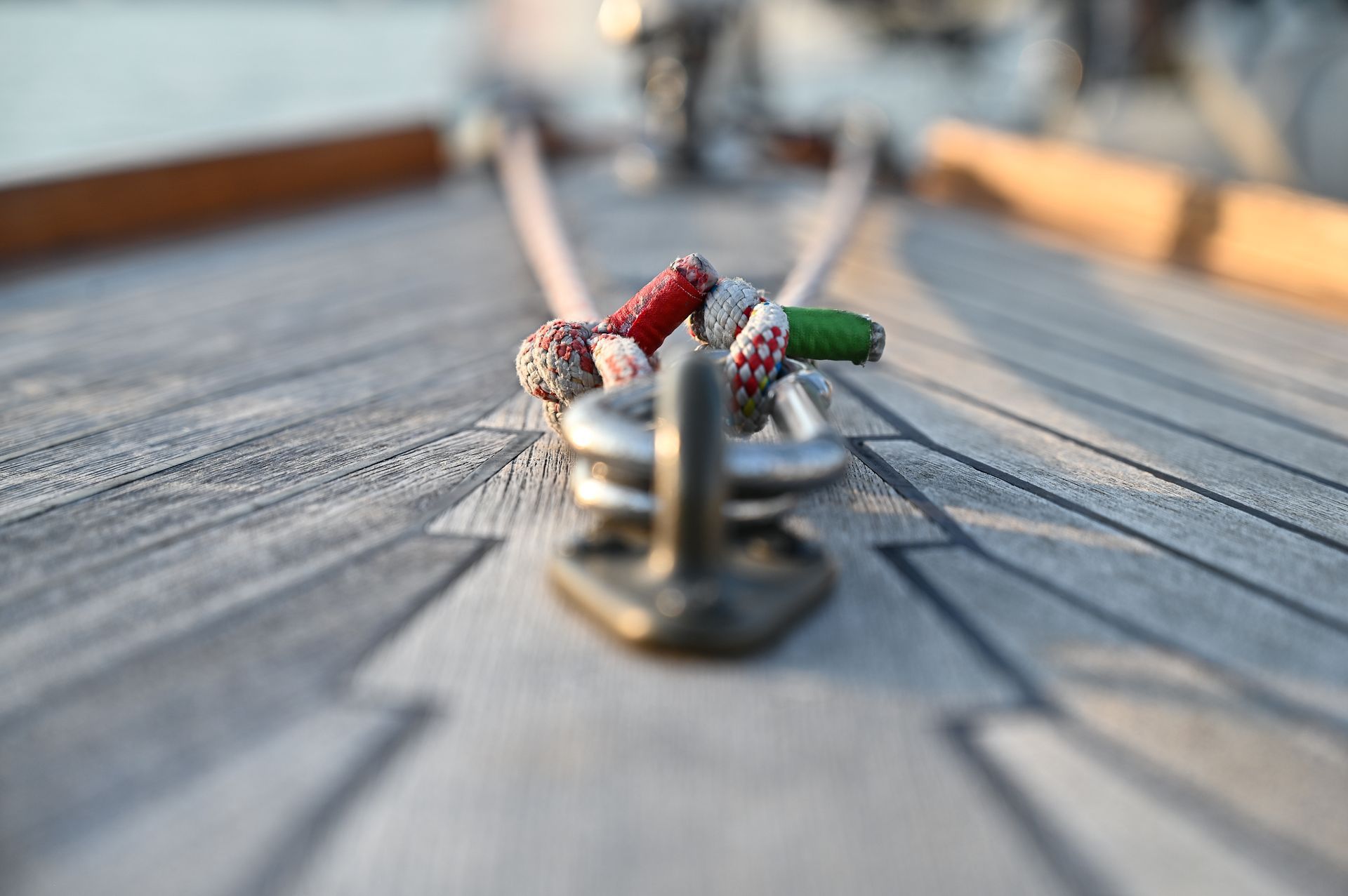 Nahaufnahme eines Segelbootdecks mit Seilen, die an einer Metallklampe befestigt sind; rote und grüne Details. Kirstin Hammerstein, hammerstein-pictures