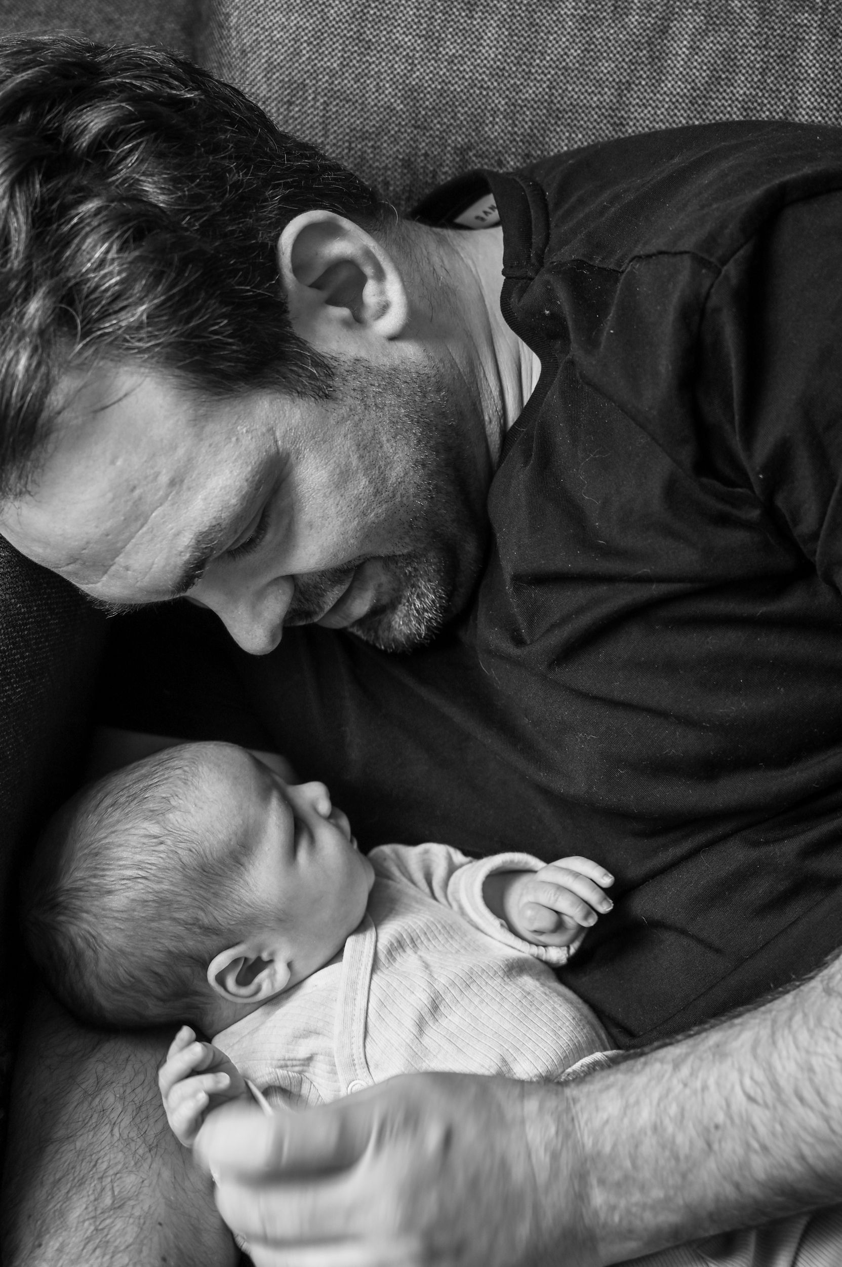 Vater blickt liebevoll auf sein neugeborenes Baby. Schwarzweißfoto, Nahaufnahme. Kirstin Hammerstein, hammerstein-pictures