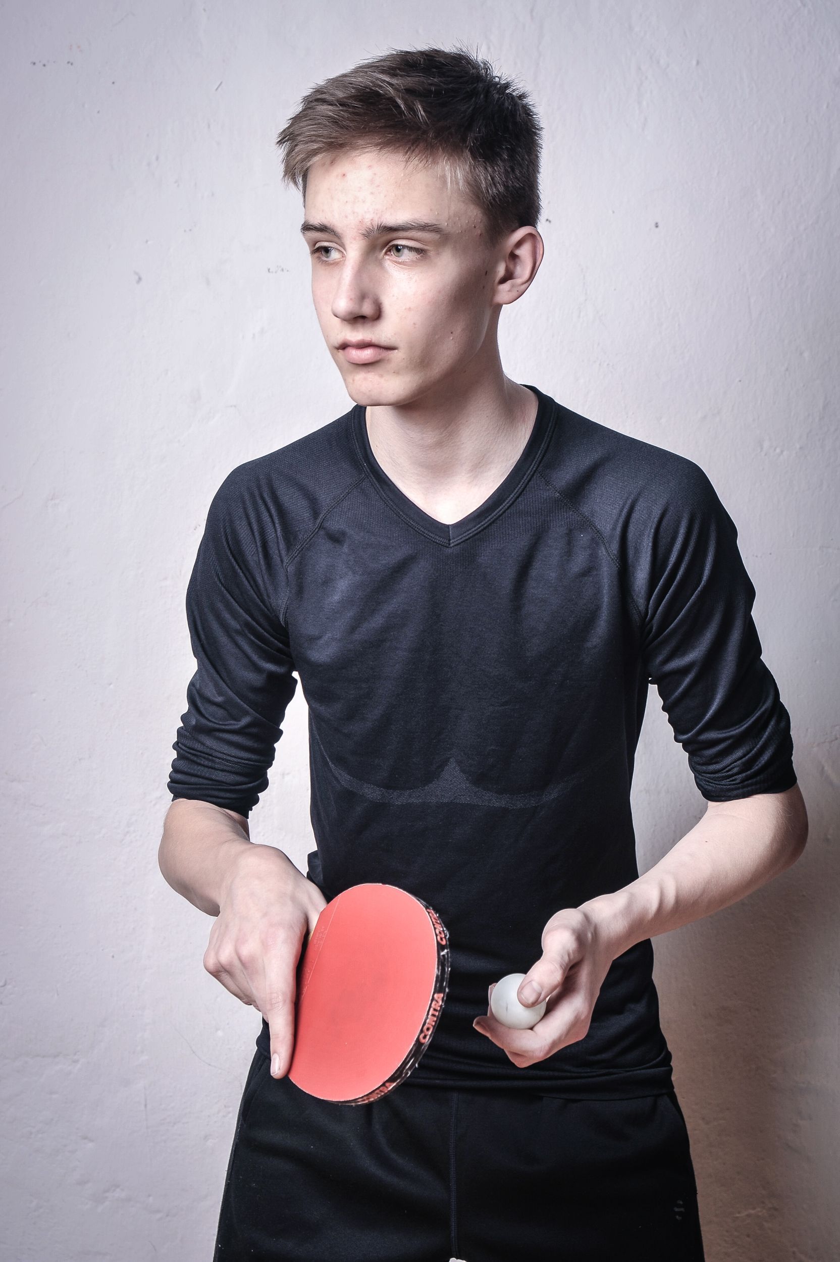 Teenager mit einem Tischtennisschläger und einem Ball, der zur Seite schaut. Kirstin Hammerstein, hammerstein-pictures