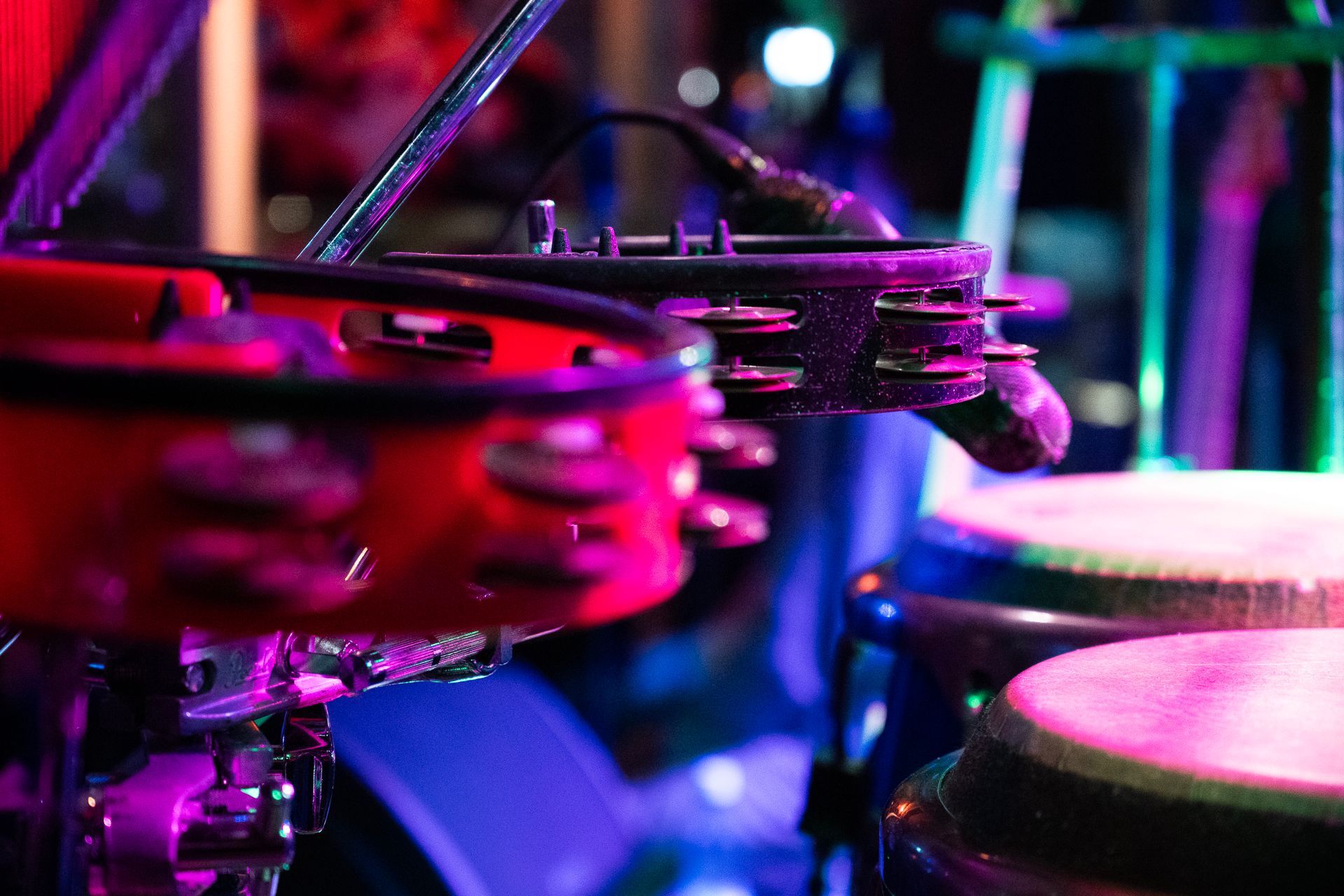Tamburine und Conga-Trommeln, beleuchtet von violetten und roten Bühnenlichtern.