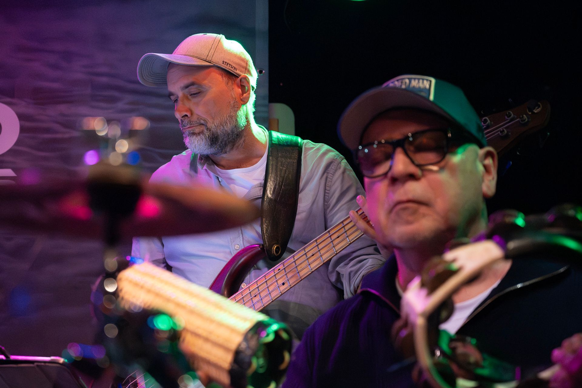 Zwei Musiker treten auf der Bühne auf: einer spielt Bassgitarre, der andere Tamburin.