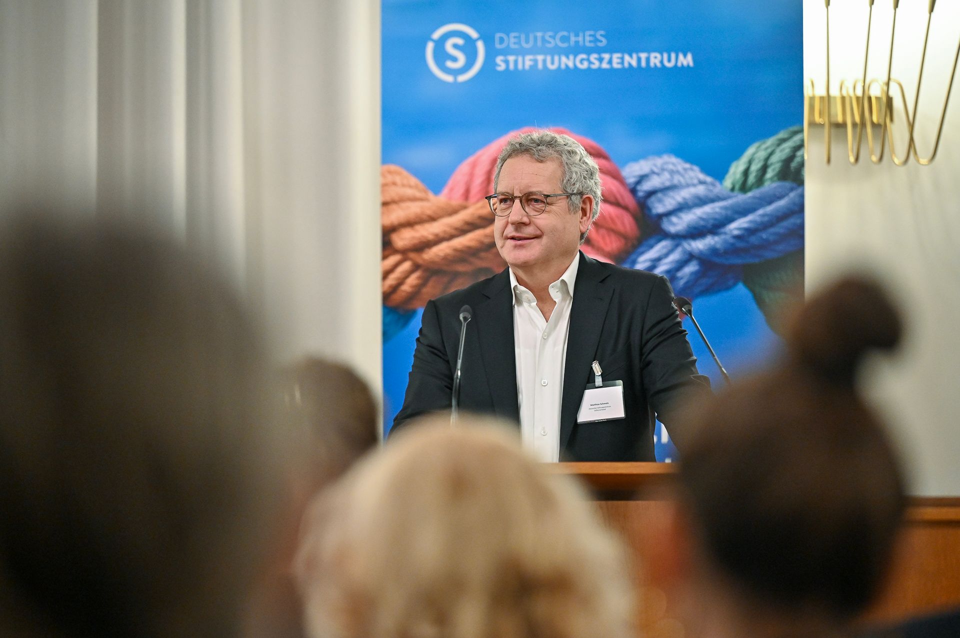 Ein Mann spricht an einem Rednerpult; im Hintergrund ist das Logo des Deutschen Stiftungszentrums zu sehen. Im Vordergrund ist das Publikum zu sehen.