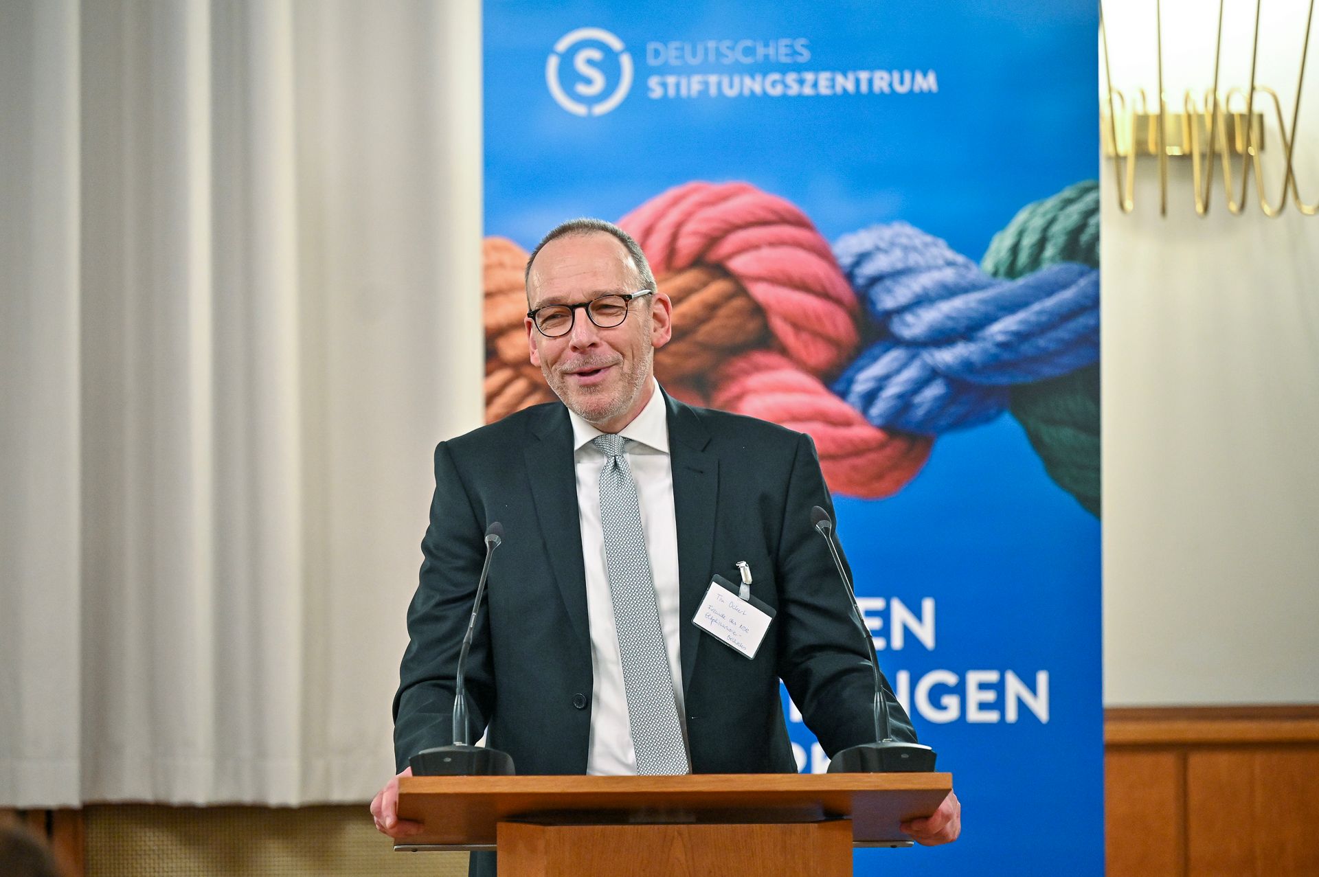 Ein Mann spricht an einem Rednerpult vor einem Banner mit dem Logo des Deutschen Stiftungszentrums.
