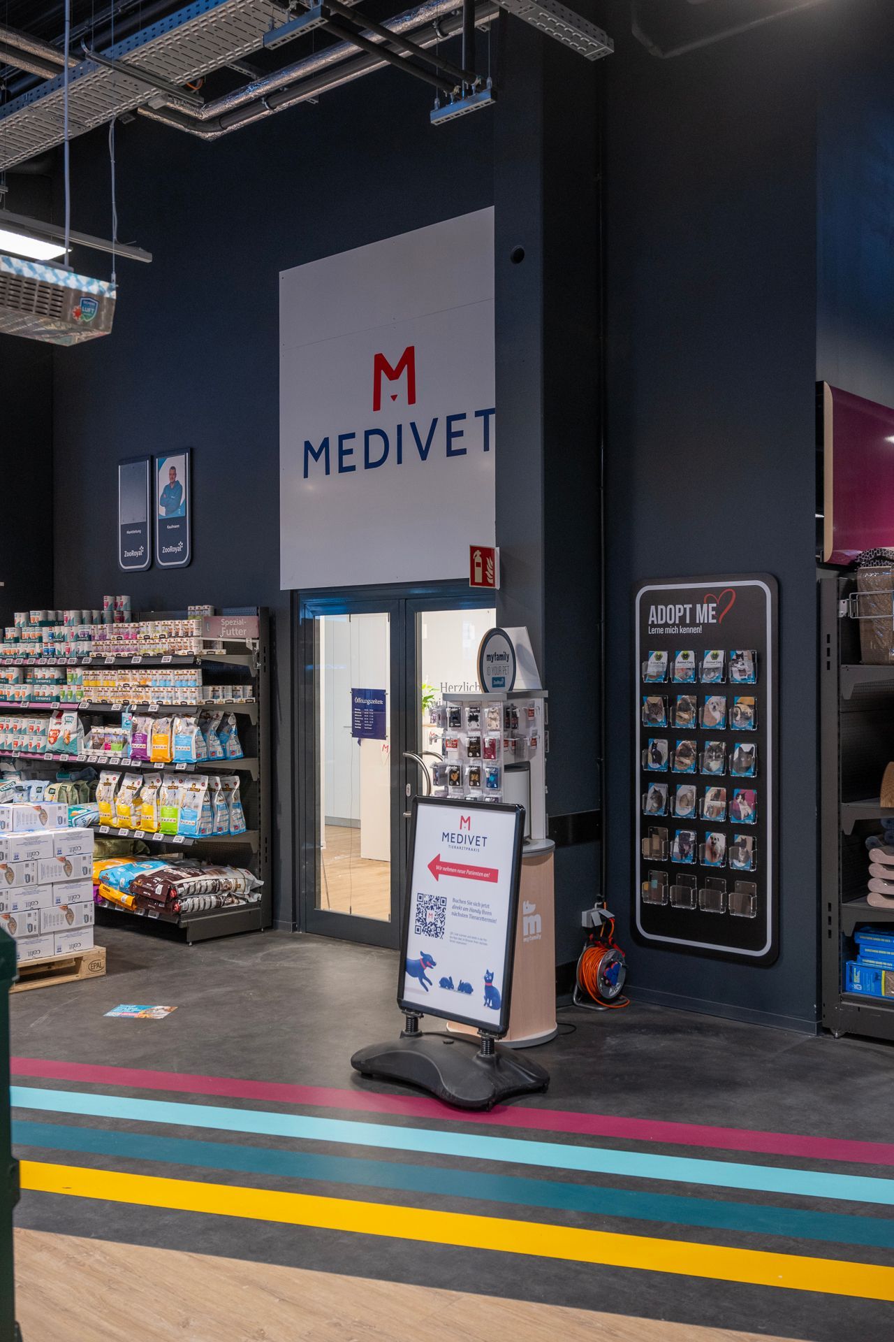 Eingang zu einer Medivet-Klinik. Das Kliniklogo befindet sich über den Türen. Regale mit Produkten sind sichtbar.