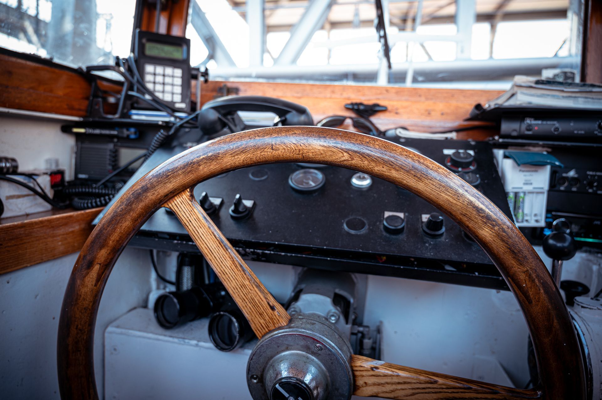 Hölzernes Schiffssteuerrad auf einem Armaturenbrett mit Instrumenten und Bedienelementen. Innenraum eines Bootes.
